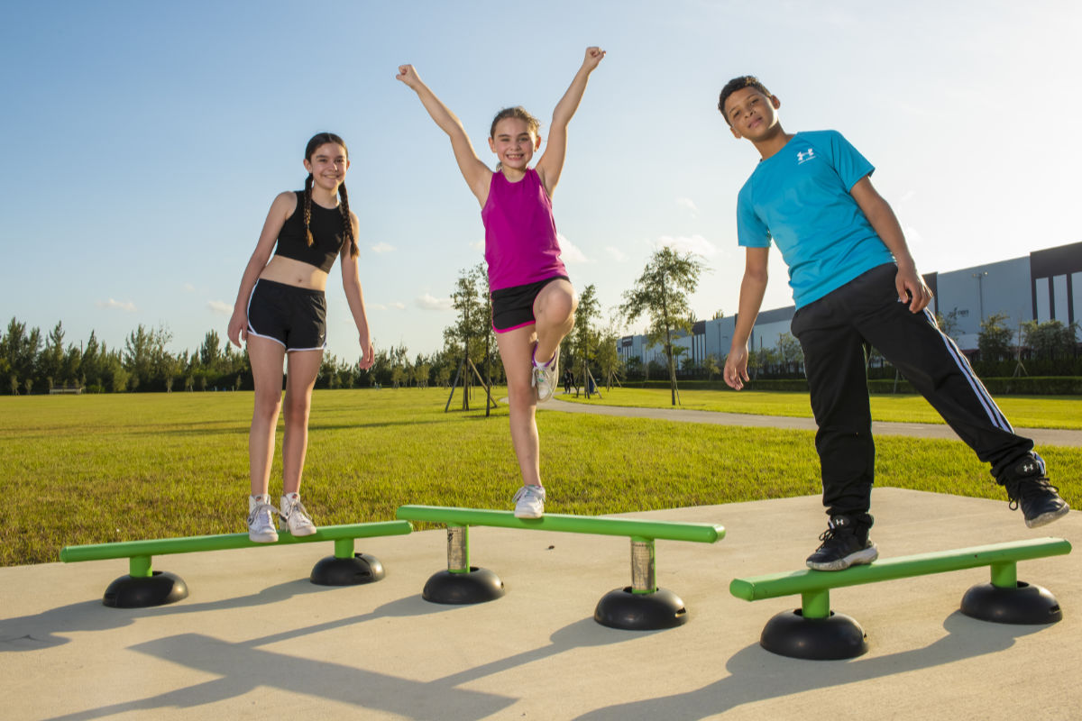 Two young girls and one young boy using ExoKids balance beam.